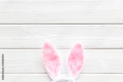 Easter bunny concept. Toy rabbit's ears on white wooden background top-down copy space
