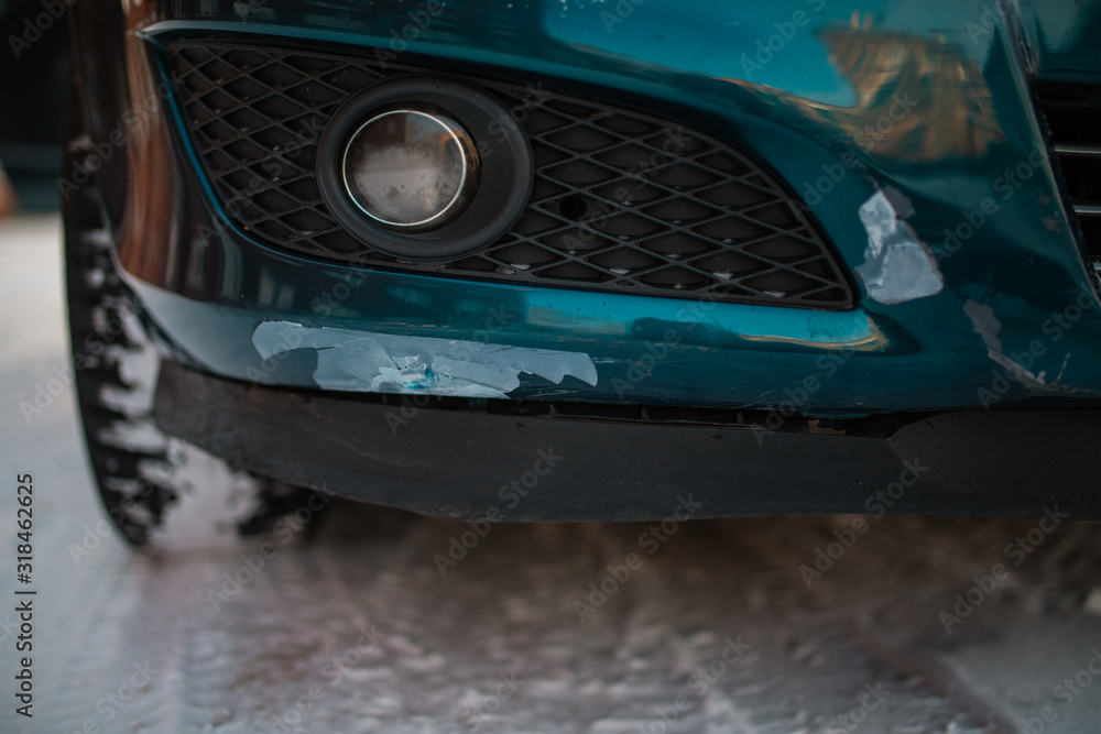 Scratches and cracks on the bumper of the green car. Broken bumper after a car crash. scratches and cracks in the car. winter snow.