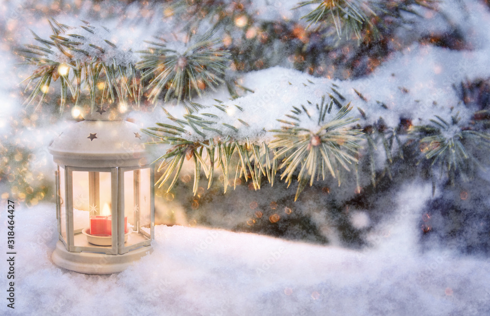 Christmas lantern with burning candle shines on snow and spruce branches, snowfall winter scene with light and bokeh Christmas lantern with burning candle shines on snow and spruce branches, snowfall winter scene with light and bokeh