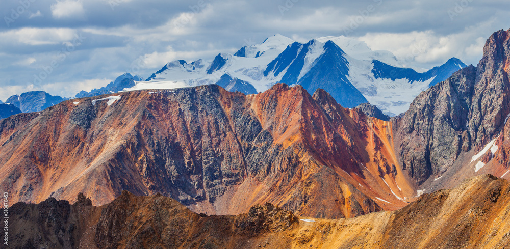 Colored cliffs and snow-capped peaks. Cloudy weather and morning light. Panoramic view.