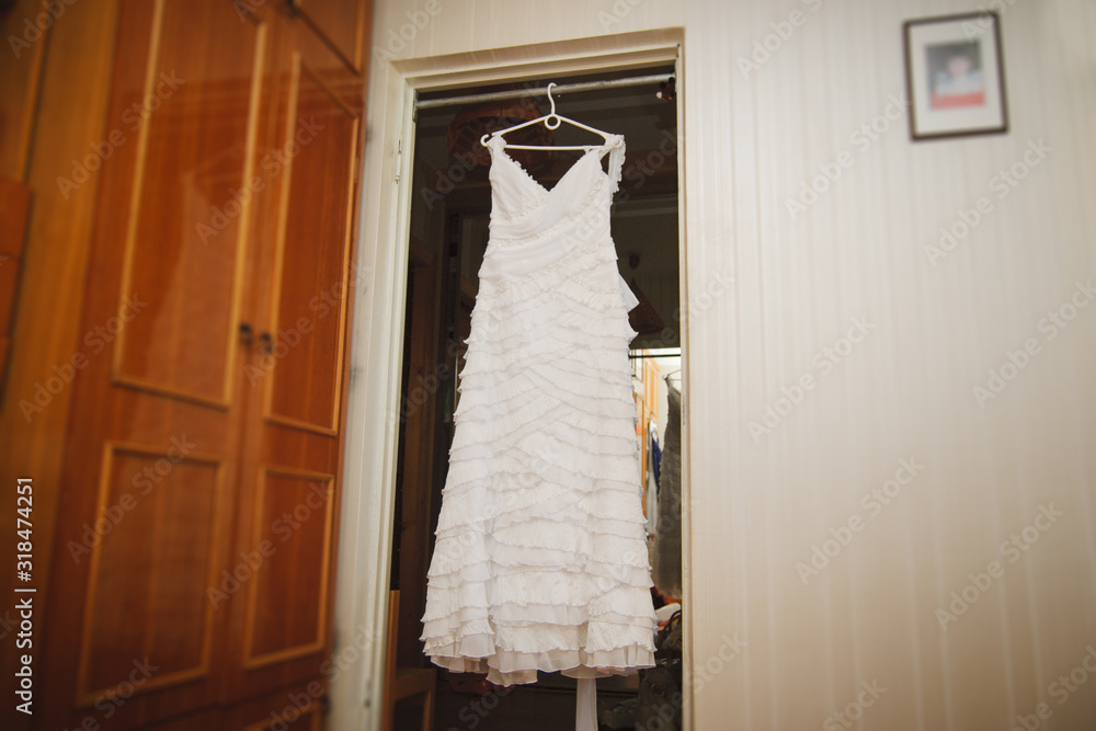The wedding dress is hanging on a hanger in the room.