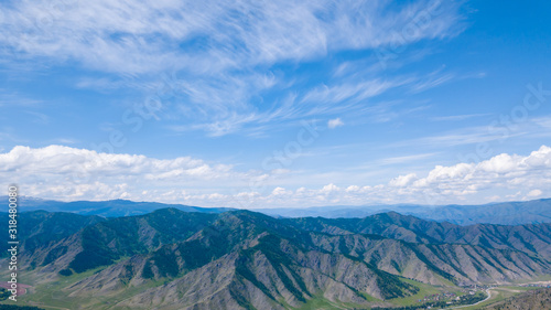 Aerial panoramic wide banner view of a Chike-Taman pass in the Altai mountains with green trees, Blue sky and clouds. © Aleksandr Kondratov