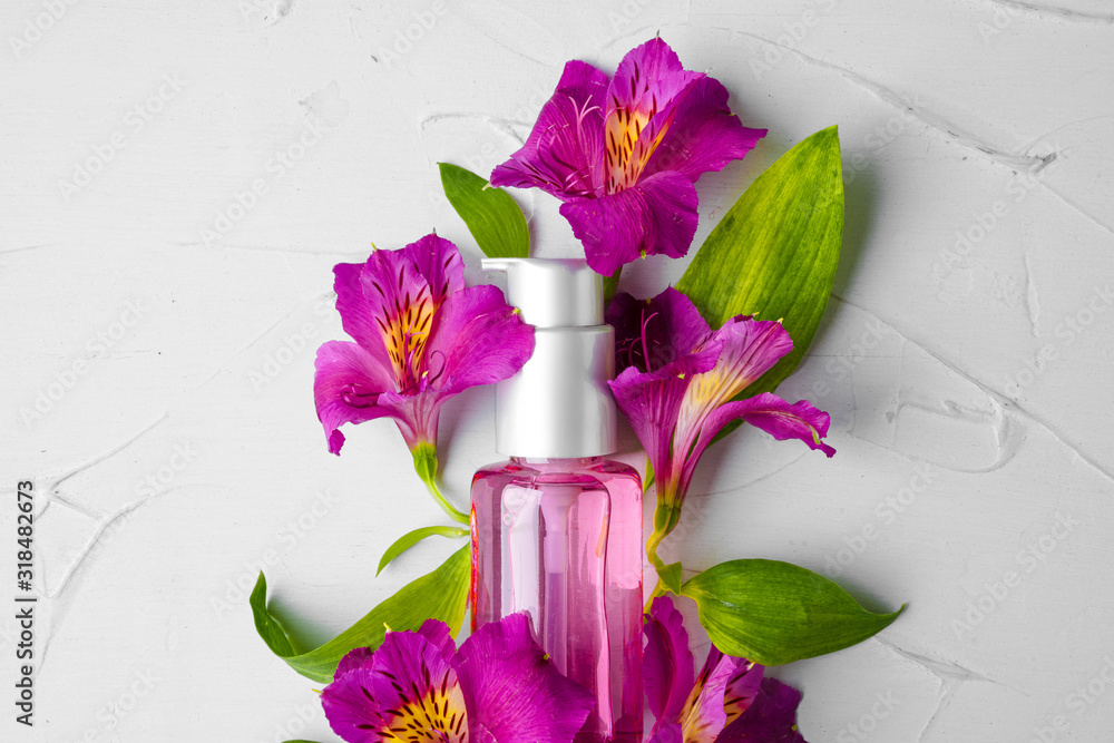 Bottle of fragrance or aromatic oil in a bunch of fresh flowers - obrazy, fototapety, plakaty 