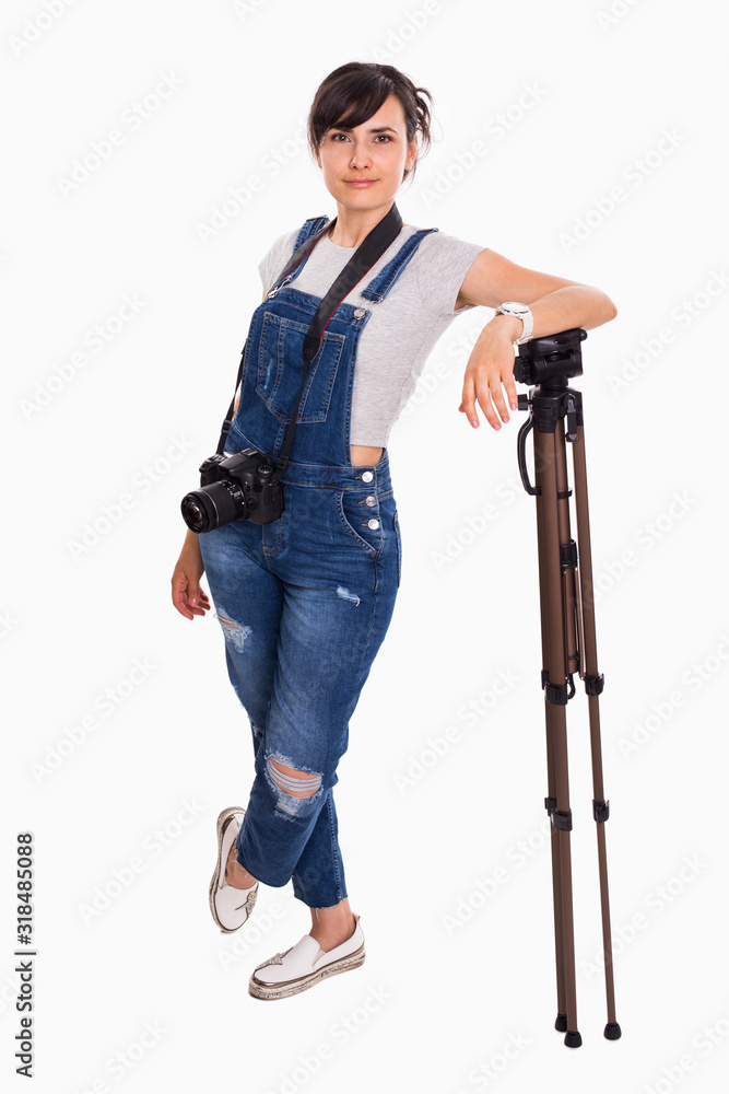 Young beautiful girl in jeans overalls with a camera on a white isolated background Young beautiful girl in jeans overalls with a camera on a white isolated background