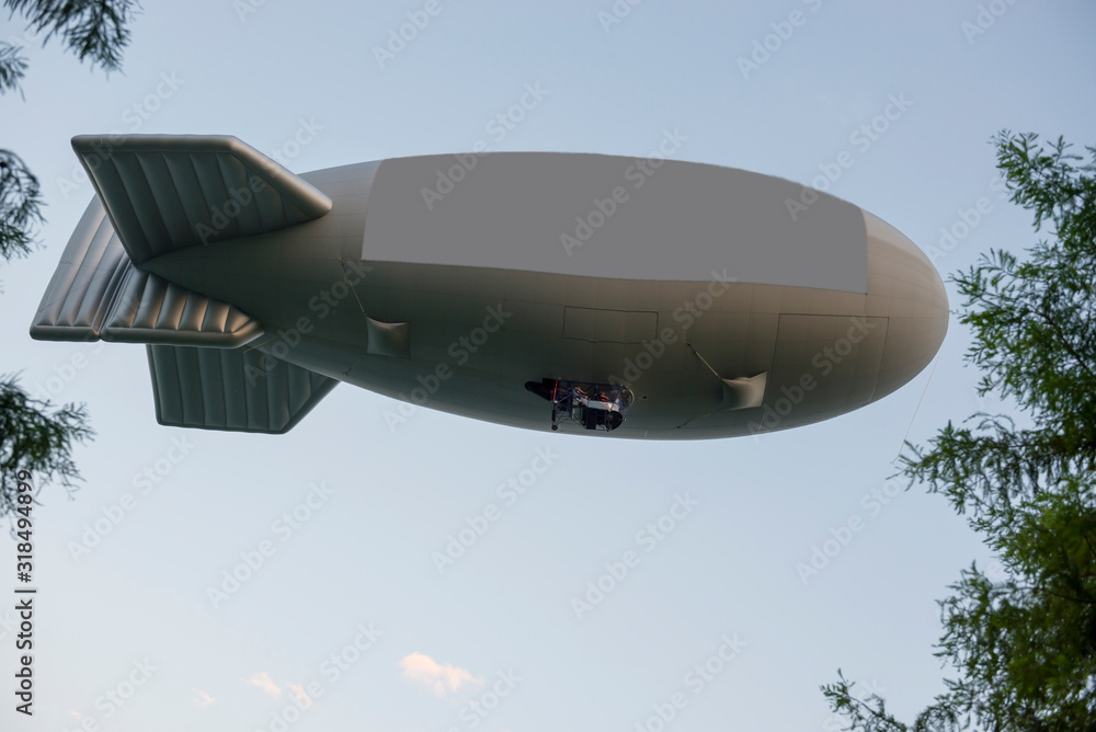 Flying Blimp with Signboard and Tree Branches with Blue Sky. Flying Blimp with Signboard and Tree Branches with Blue Sky.
