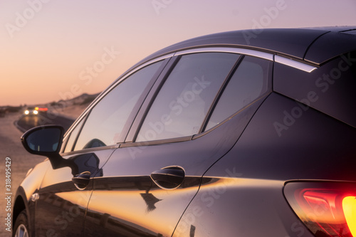 Silhouette of a car standing on the side of the desert road - close-up