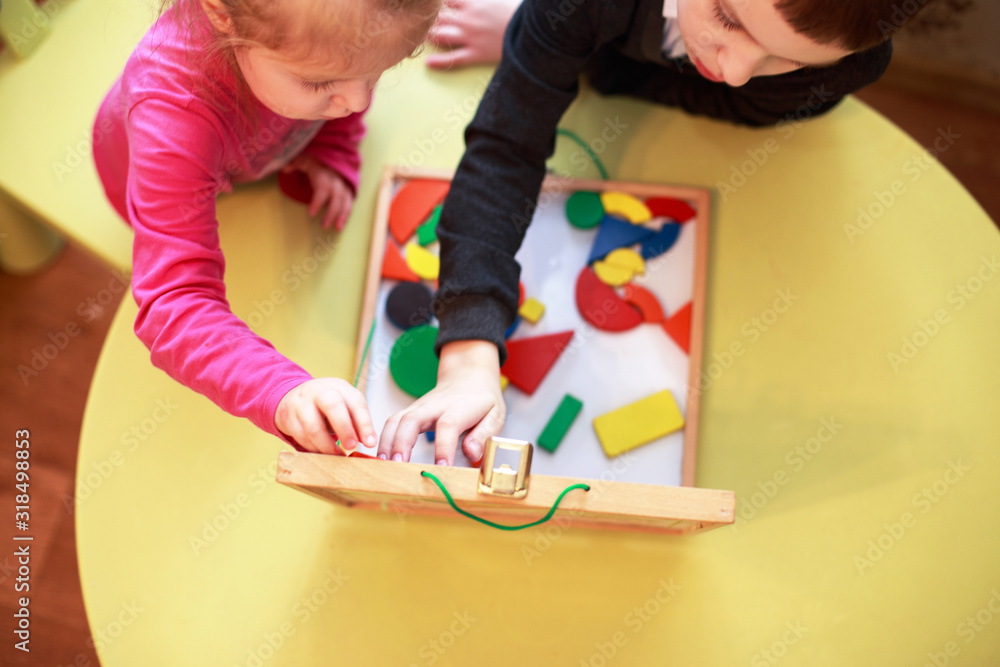 children play wooden magnetic educational games together. view from above. kids play with a constructor children play wooden magnetic educational games together. view from above. kids play with a constructor