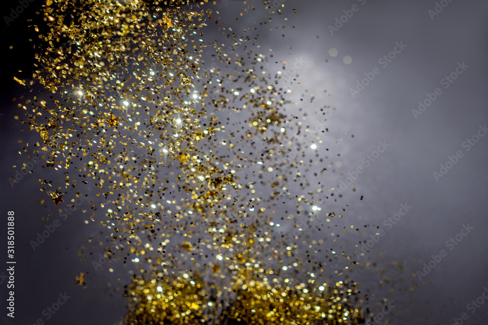 Abstract dark background with flying sequins as stars. A festive concept. Flying sparkles.
