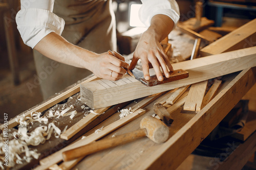 Man working with a wood. Carpenter in a white shirt photo