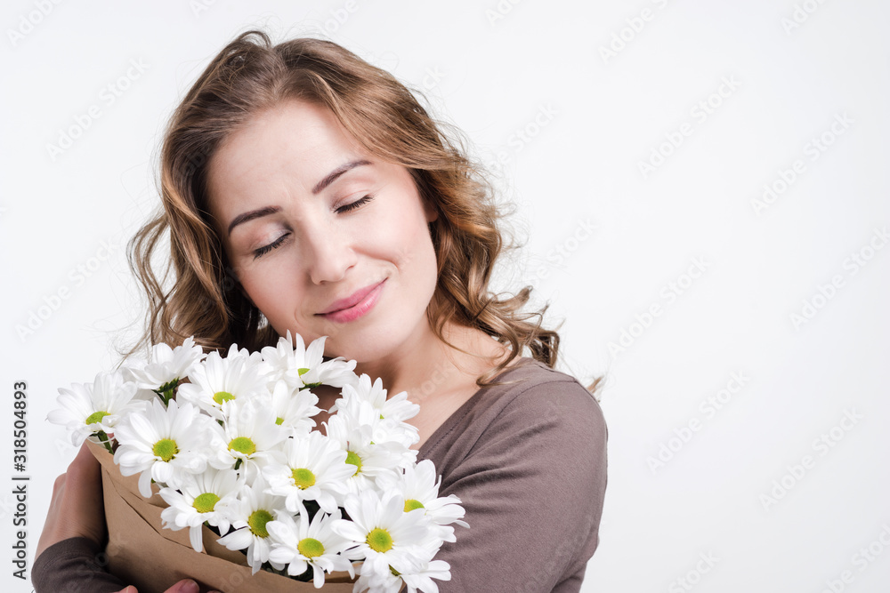 Girl holding flowers in studio on white wall background