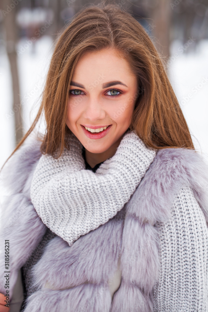 Portrait of a young beautiful brunette girl in fur vest posing in winter park Portrait of a young beautiful brunette girl in fur vest posing in winter park