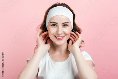 Foto Honestly smiling young woman in a hair bandage posing on a pink background