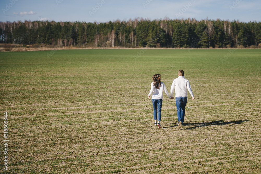Happy girl and guy running and hugging on the field, love story travel concept, selective focus Happy girl and guy running and hugging on the field, love story travel concept, selective focus