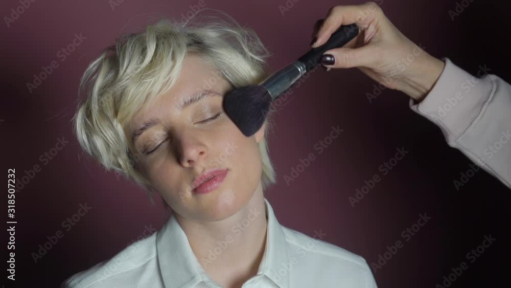 Makeup artist applying makeup on the face of the model in studio Makeup artist applying makeup on the face of the model in studio