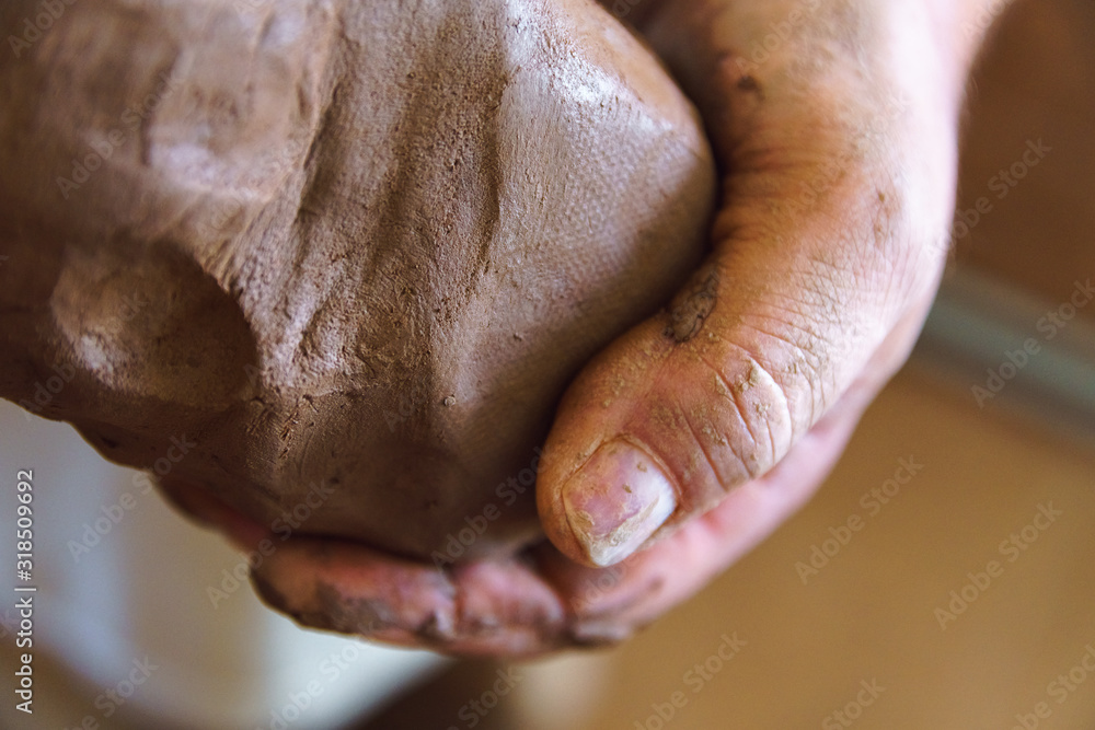 Obraz premium Male hand holds piece of clay.