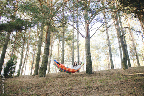Couple in love, girl and guy in hammock enjoys in the woods, travel love story concept