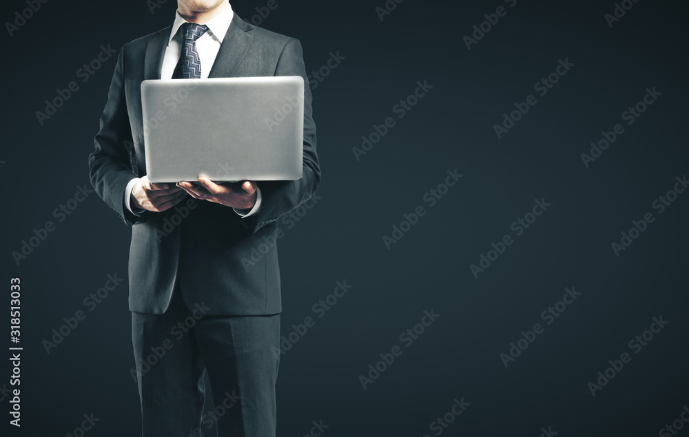 Businessman in suit holding laptop on black background. Technology and communication concept. Close up Businessman in suit holding laptop on black background. Technology and communication concept. Close up