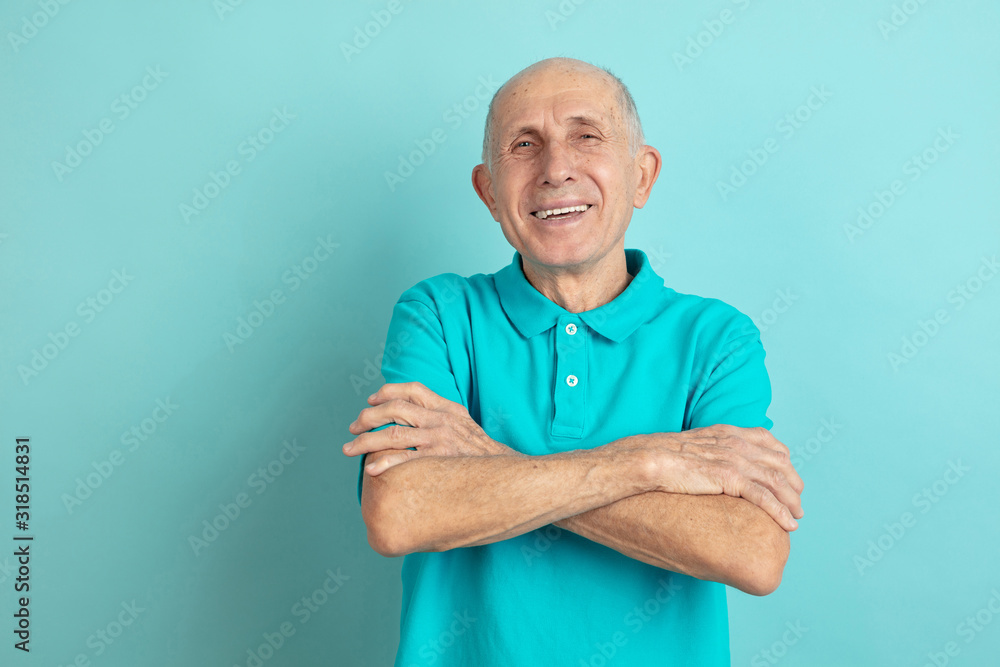 With hands crossed. Caucasian senior man's portrait isolated on blue studio background. Beautiful male emotional model. Concept of human emotions, facial expression, sales, wellbeing, ad. Copyspace. With hands crossed. Caucasian senior man's portrait isolated on blue studio background. Beautiful male emotional model. Concept of human emotions, facial expression, sales, wellbeing, ad. Copyspace.