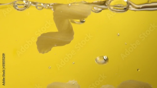 Mouth-watering pasta fall into boiling water on yellow background. Slow motion photo