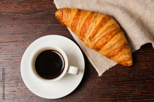 Tasty rustic breakfast. Croissant and coffee in white cup, top view, flat lay