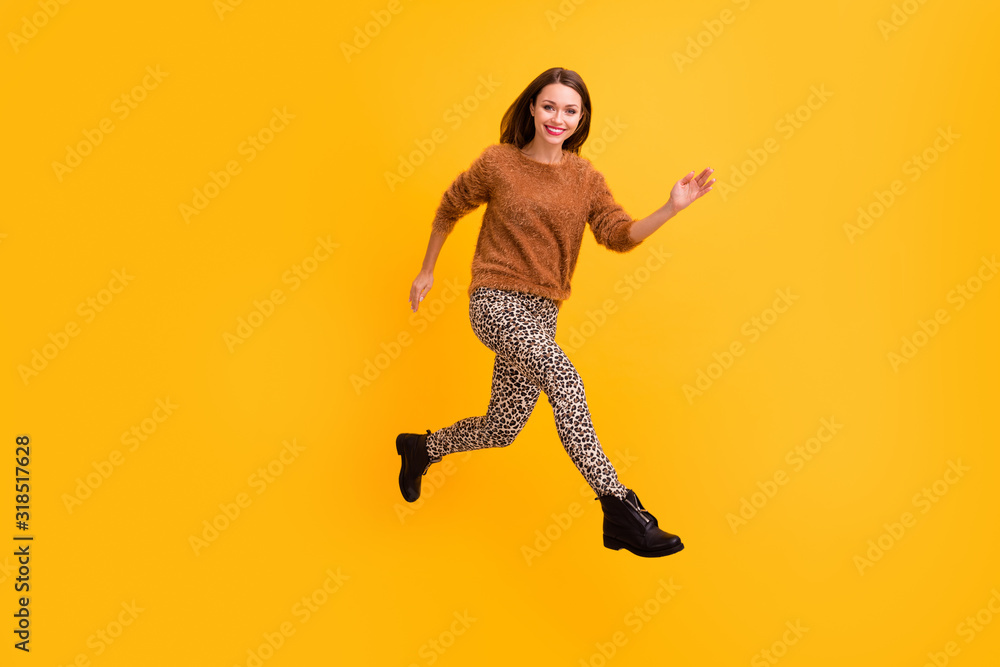 Full length photo of pretty traveler lady jump high fast rushing shopping low prices abroad sale wear fluffy pullover leopard pants footwear isolated yellow color background Full length photo of pretty traveler lady jump high fast rushing shopping low prices abroad sale wear fluffy pullover leopard pants footwear isolated yellow color background