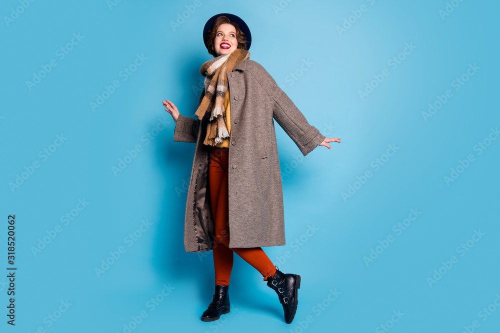 Full length photo of pretty traveler lady walk street good mood day lucky trip abroad wear casual long grey coat scarf trousers cap footwear isolated blue color background