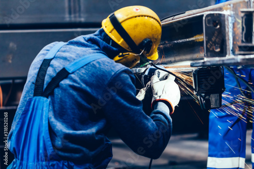Fotografija Worker grinding in a workshop. Heavy industry factory