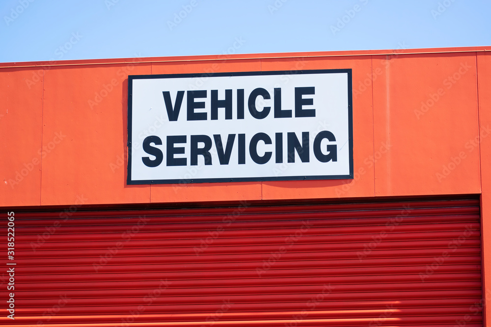 View of vehicle servicing sign with black text on white background above garage door