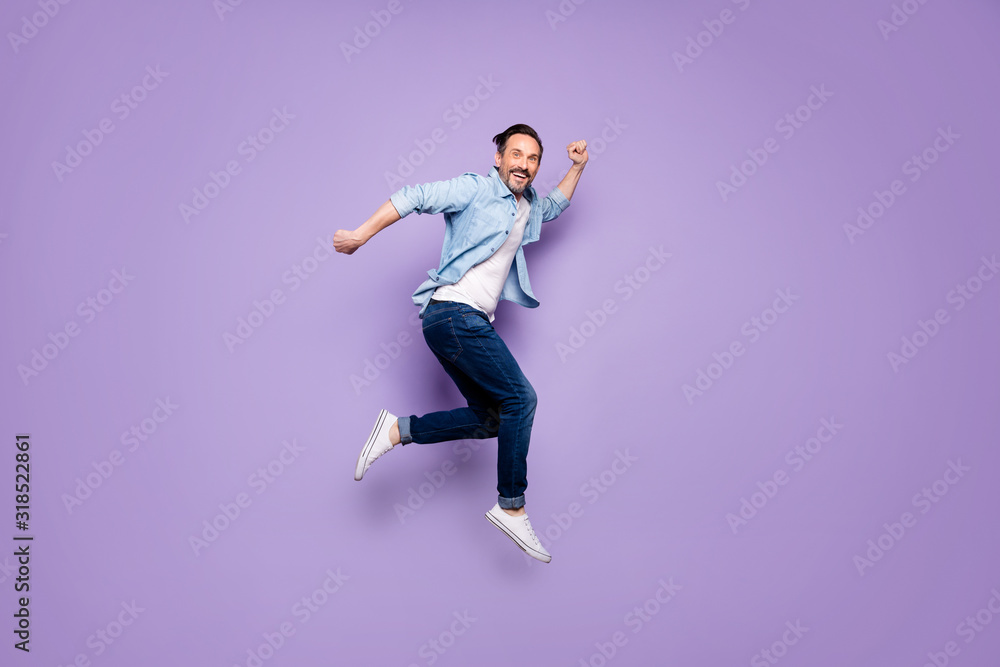 Full body profile side photo of crazy cheerful man jump have rest relax run after spring time sales discounts wear good looking clothing isolated over violet color background Full body profile side photo of crazy cheerful man jump have rest relax run after spring time sales discounts wear good looking clothing isolated over violet color background