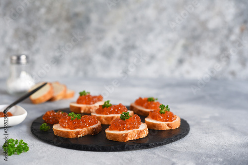 Toast bread with red caviar. Sandwich with caviar and butter on a concrete background.
