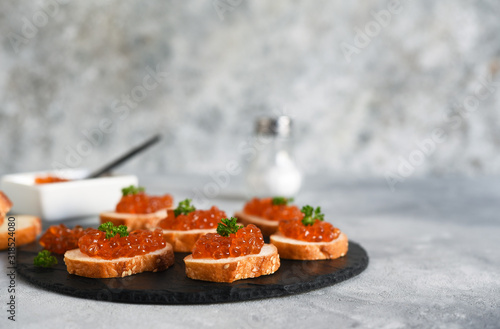 Toast bread with red caviar. Sandwich with caviar and butter on a concrete background.