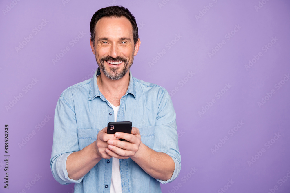 Portrait of positive cheerful man use cell phone have rest relax text type sms chatting with friends wife wear stylish clothing isolated over purple color background Portrait of positive cheerful man use cell phone have rest relax text type sms chatting with friends wife wear stylish clothing isolated over purple color background