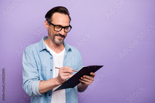 Portrait of cheerful concentrated man hold clip board write tips he need in professional working wear good looking outfit isolated over violet color background