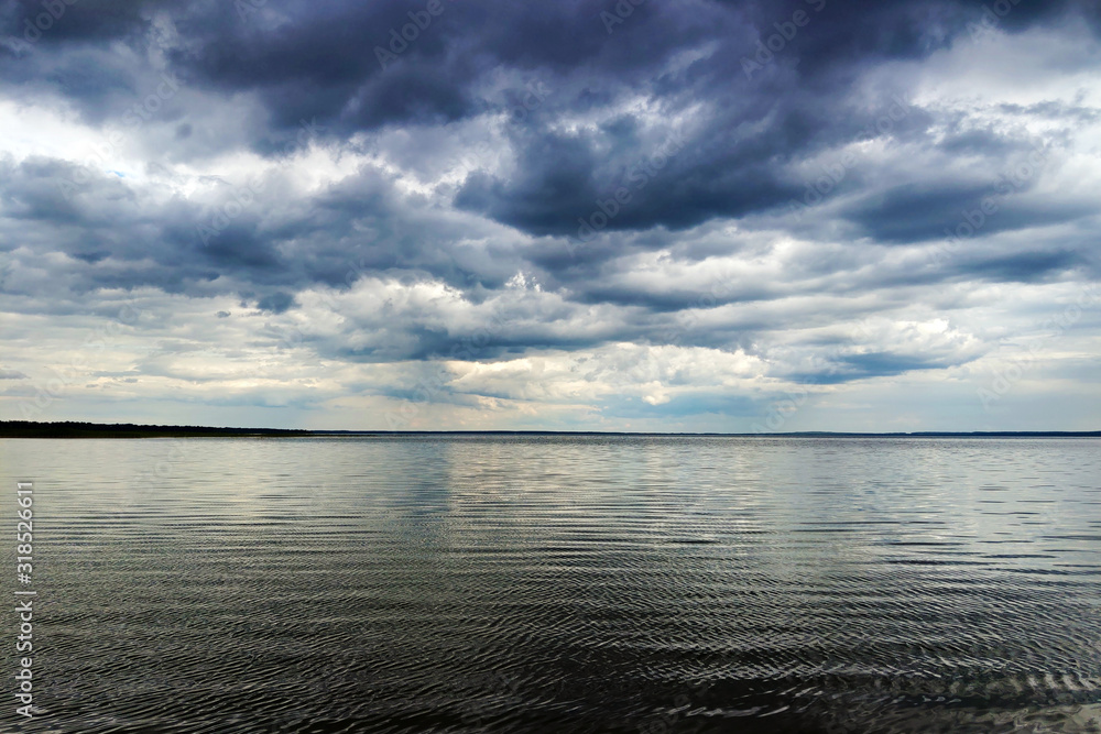 Obraz premium Moon shining through dark clouds over water, atmospheric background.