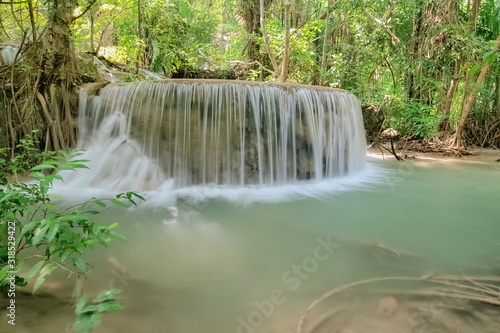 Beautiful blue-green water flowing  on cliff rocks around with green forest background, Erawan Waterfalls 6th. Level, Erawan National Park, Kanchanaburi, Thailand.