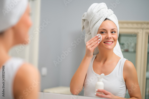 Portrait of young woman who is cleaning skin on her face.