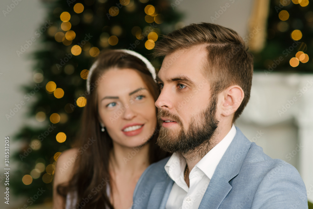 Attractive and loving man and girl on the background of the Christmas tree at home, the concept of Christmas love story