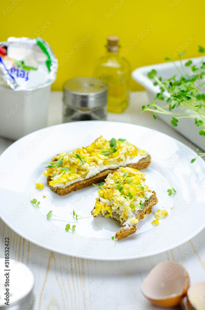 Healthy whole wheat bread with feta cheese, scrambled eggs and microgreens, proper nutrition sandwiches for breakfast