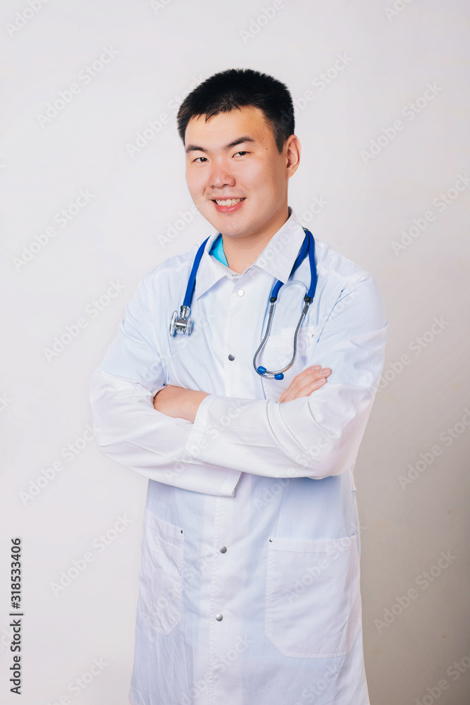 Asian doctor in a white coat with a stethoscope on a white background. Studio portrait of a handsome guy in white medical clothes Asian doctor in a white coat with a stethoscope on a white background. Studio portrait of a handsome guy in white medical clothes