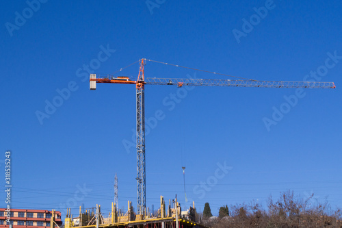construction crane against the background of a house under construction and blue sky
