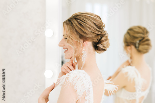 Portrait of a beautiful young bride in a bright room in a romantic atmosphere. Bride in a negligee with wedding hair and makeup