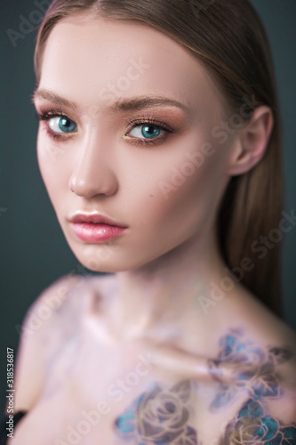 Studio portrait of a model. Body art gray roses. Beautiful girl on gray background