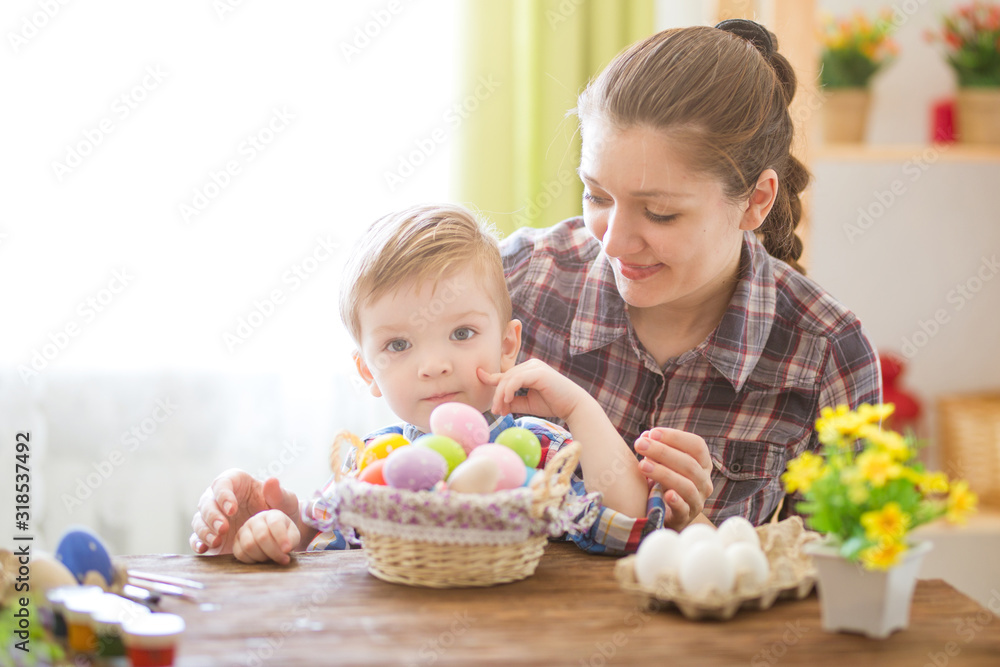 Happy time while painting easter eggs. Easter concept. Happy mother and her cute child getting ready for Easter by painting the eggs Happy time while painting easter eggs. Easter concept. Happy mother and her cute child getting ready for Easter by painting the eggs