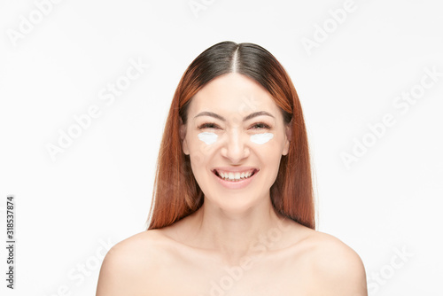 Smiling woman with cream under eyes