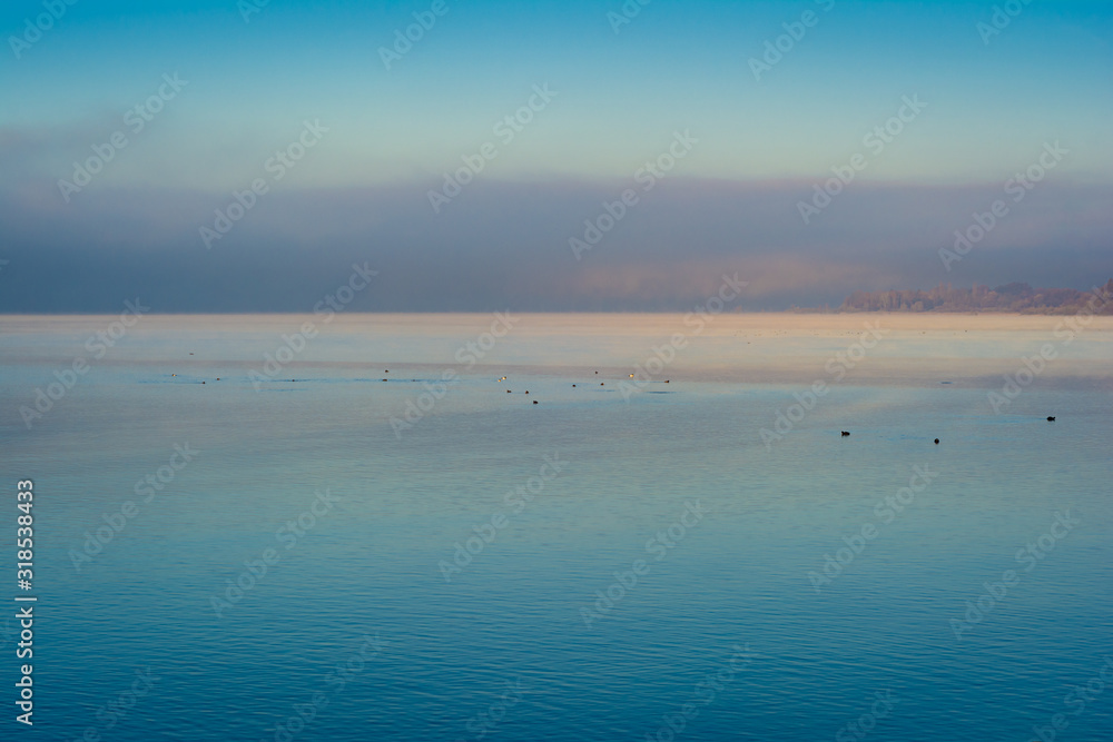 Sonnenaufgang am See mit Nebel im Winter