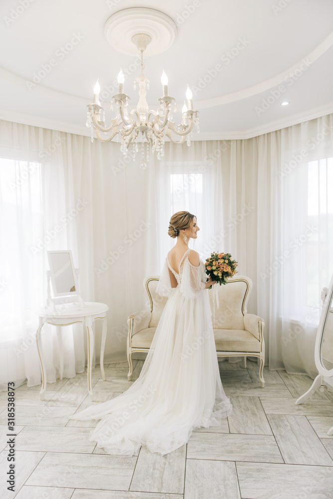 Portrait of a beautiful young bride in a bright room in a romantic atmosphere. Bride with a bouquet of flowers