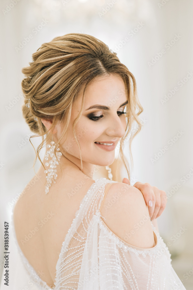 Portrait of a beautiful young bride in a bright room in a romantic atmosphere. Close-up of wedding makeup and hairstyle