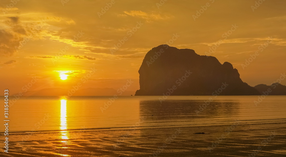 view panorama seaside evening of mountain in golden sea with yellow sun light in the sky background, sunset at Pak Meng Beach, Trang Province, southern of Thailand.