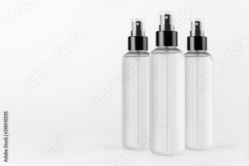 Three tall transparent spray dispenser bottles for cosmetics with liquid on white background, mock up for branding, presentation, design.