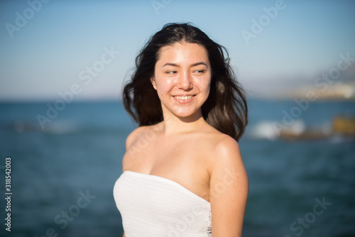 Smiling Young Woman Looking Away While Standing Against Sea On Sunny Day © benjamin egerland/EyeEm